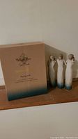 Photo showing the three Willow Tree Susan Lordi figurines standing next to their original box with matching colors and text.