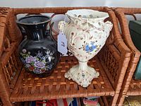 Two decorative vases on a woven tray, showing the black Japanese vase and the cream Italian urn vase side by side
