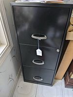 Front view of the black steel filing cabinet showing three drawers, chrome handles, and key lock on top drawer.