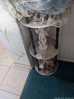 Full view of the 3 tier marble and wood stand showing the top, middle, and bottom marble shelves supported by dark wood turned legs.