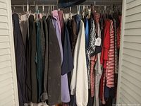 Wide view of hanging clothes showing jackets, tops, and shirts in various neutral, dark, and colorful shades.