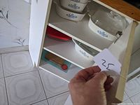Photo of cupboard with Corning Ware Blue Cornflower dishes, showing shelves and partial view of cupboard contents.