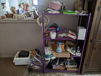 Full view of purple metal shelving unit with various items including shoes, cleaning supplies, and boxes