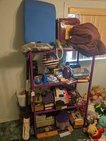 View of purple shelving unit with various mixed decor and household items including candlesticks, shoes, globe, and plush toys