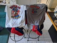 Lot showing two t-shirts draped over chairs with two Boston Red Sox socks underneath