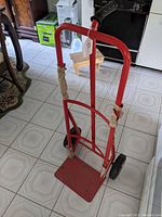 Full front view of the red steel hand truck showing frame, handles, and rubber wheels.