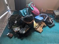 Overview of the collection piled on floor showing various purses and handbags in different colors and designs.