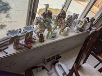 Wide shot of shelf displaying all figurines, planters, and vases on window sill