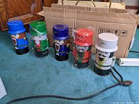 Set of five tin nutcracker canisters displayed upright, each with different colored hats and fully visible designs.