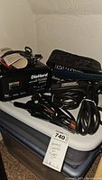 DieHard battery charger and jumper cables set on a storage bin