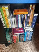 Photo of assorted audiobooks in cassette and CD format arranged on a shelf, showing visible titles and cases.