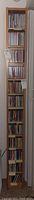 Full view of tall, thin wooden CD tower filled with CDs. Shows 12 shelves with CDs neatly organized.