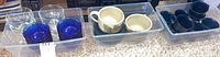 Overall view of all dishware items showing mugs, bowls, and glasses in plastic bins