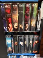 Photo showing Buffy the Vampire Slayer seasons 1 through 7 DVD sets and Season 8 Motion Comic Blu-ray, alongside Angel seasons 1 through 5 DVD sets arranged vertically with visible cover art and season numbers.