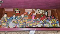 Wide view of the lot showing six colorful finger puppets, animal puppets and two dolls arranged in a display case