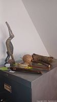 The lot including hornbill bird sculpture, flute, spin drum, and gourd rattles arranged on a metal filing cabinet surface.