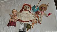 Overview of six dolls and puppets including handmade Raggedy Ann and Mexican marionette on white background