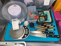 Photo showing all items arranged on a blue surface including ceramic sushi plates, chopsticks, knives, salad spinner, kitchen scale, and salt and pepper shakers.
