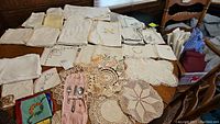 Overview of vintage linens, embroidered linens, and various crocheted and tatted doilies laid out on table