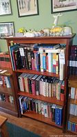 Front view of wooden bookcase filled with books and animal figurines on top, showing scratches on wood finish.