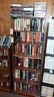 Shelf showing a mixture of books and DVDs, mostly novels and history books with DVDs on the top shelf