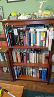 Wide shot of a wooden bookshelf filled with various music themed books and some ceramic animal figurines on top.