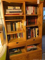 Full view of wooden shelving unit filled with books, drawers, and cabinet doors visible