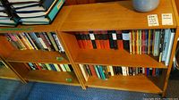 Two wooden bookcases filled with various books on history, biography, and fiction