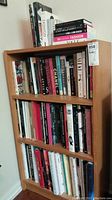 Bookcase with two shelves, filled with assorted fashion and art books, top shelf with additional stacked titles