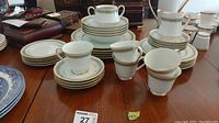 Full view of Noritake china set arranged on table including stacked plates, bowls, cups, creamer, and sugar bowl without lid