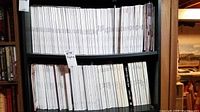 Wide view of black shelving unit filled with magazines and books including History of 20th Century Fashion titles