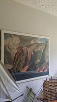 A.J. Casson mounted print showing landscape with cliffs and water, visible water stains, framed on wall beside sailboat models.