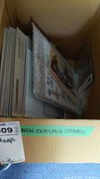 Box filled with folders and plastic sleeves containing New Zealand stamps, labeled 'New Zealand Stamps'.