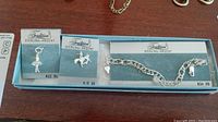 Shows the bracelet with two charms on a Tradition Sterling-Argent branded box with prices indicated.