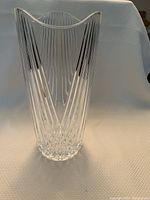 Front view of the crystal glass vase showing vertical cut patterns, clear transparent glass, and scalloped top edge.