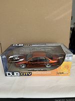 Front and side view of the diecast Chevy Impala SS model in original box showing metallic orange paint and chrome rims.