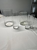 Group photo of all five clear glass vases in various shapes and sizes arranged on a white surface.