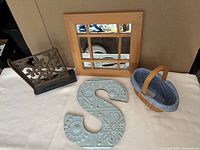 Photo showing all four items in the lot: oval woven basket with fabric liner, metal letter 'S', small wooden framed mirror, and iron wood bookend.