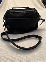 Front view of black Lug Scoop Bag showing zippered compartments and adjustable strap
