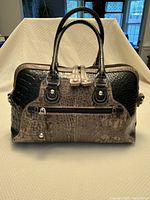 Front view of black croco embossed leather handbag showing double drop handles, front zip pocket, and visible texture and hardware.