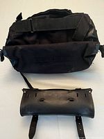 Top view of the black Nelson-Riggs roll bag showing main compartment zipper and attached leather fork bag with straps and buckle slots.