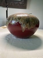 Side view of rounded ceramic gel fuel burner pot with textured green and brown glaze over red base.