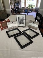 Seven assorted picture frames on a white tablecloth including five 4x6 and two 5x7 frames