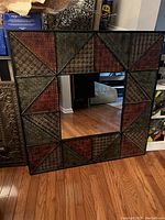 Full front view of the large square mirror showing the embossed metal frame with multi-color sections around the mirror glass.