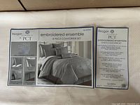 Photos of box and label showing brand Reagan PCT and contents of embroidered ensemble 8 piece comforter set