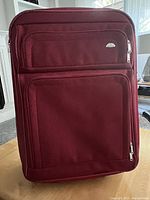 Front view of burgundy fabric Samsonite luggage showing rectangular shape and zippered compartments.