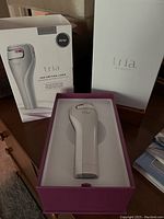 Tria Age-Defying Laser device inside original pink and white box with packaging and outer sleeve visible