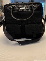 Front view of the black quilted Vera Bradley weekend bag with two front flap pockets and black handles and shoulder strap.