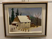 Full view of framed signed original oil painting showing a snow-covered barn and farm landscape with trees and mountain background.