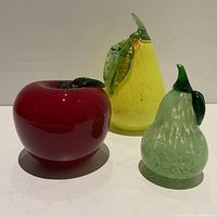 Front view of three Murano blown glass fruits on a white surface.